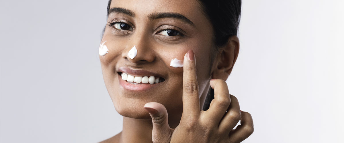 Woman applying sunscreen to nose and cheeks