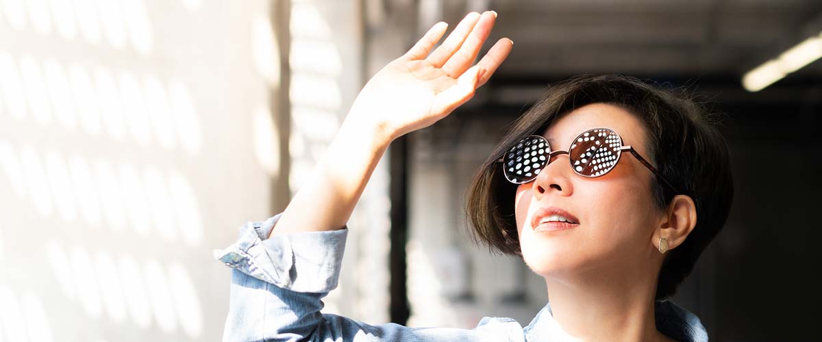Woman in sunglasses shielding sun from face