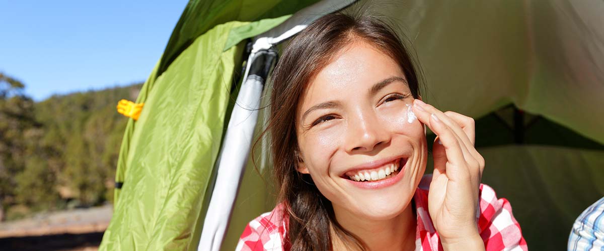 Smiling woman wearing a sun screen while camping